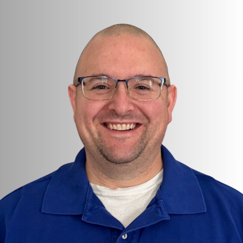 Smiling bald man wearing glasses and a blue shirt.